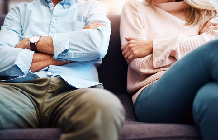 Divorced couple sitting on couch with arms crossed