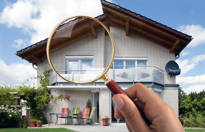 Using magnifying glass to inspect outside of house